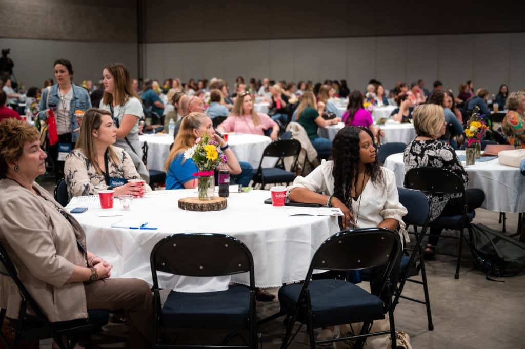 a group of people gathered around tables in an indoor setting.