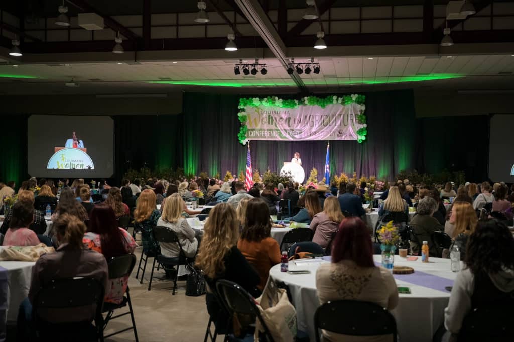 An indoor event with people at tables, watching a stage presentation.