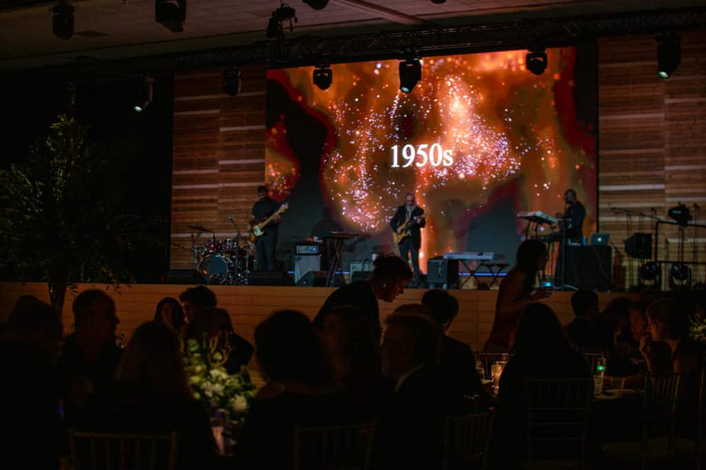 A live performance with fiery visual effects and a bright "1950s" sign.