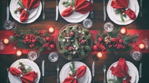 Elegant holiday event venue Alexandria table setting with red napkins, candles, and festive greenery for a Christmas celebration.