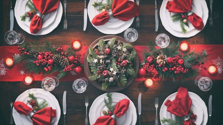Elegant holiday event venue Alexandria table setting with red napkins, candles, and festive greenery for a Christmas celebration.