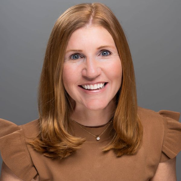 A woman wearing a brown top positioned in front of a grey background